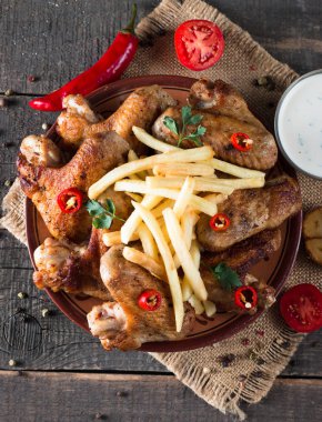 Yakın çekim fotoğraf Barbekü tavuk kanatlı patates ve bira. Barbekü soslar, ketçap, mayonez etli. Hızlı ve abur cubur kavramı. 