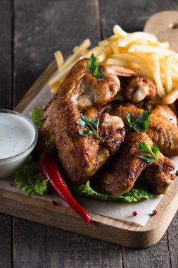 Yakın çekim fotoğraf Barbekü tavuk kanatlı patates ve bira. Barbekü soslar, ketçap, mayonez etli. Hızlı ve abur cubur kavramı. 