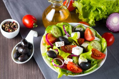 Kiraz domates, ruccola, roka, beyaz peynir, zeytin, salatalık, soğan ve baharat taze Yunan salatası yaptı. Sezar salatası ahşap arka plan üzerinde beyaz bir kase. Sağlıklı organik beslenme gıda kavramı.