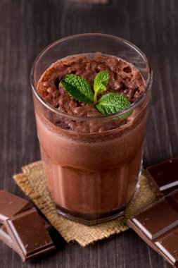 Çikolata, kahve, süt, muz sallamak ahşap arka plan üzerinde. Nane ile güler yüzlü. Milkshake. Protein diyeti. Sağlıklı yiyecek ve içecek konsepti.