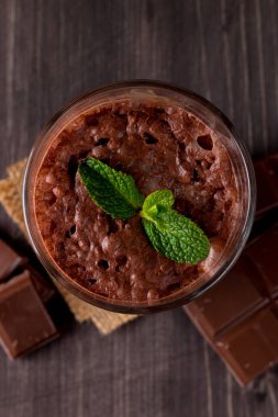 Çikolata, kahve, süt, muz sallamak ahşap arka plan üzerinde. Nane ile güler yüzlü. Milkshake. Protein diyeti. Sağlıklı yiyecek ve içecek konsepti.