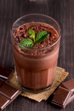 Çikolata, kahve, süt, muz sallamak ahşap arka plan üzerinde. Nane ile güler yüzlü. Milkshake. Protein diyeti. Sağlıklı yiyecek ve içecek konsepti.