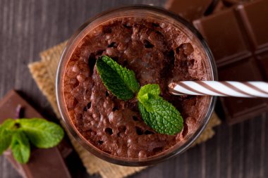 Çikolata, kahve, süt, muz sallamak ahşap arka plan üzerinde. Nane ile güler yüzlü. Milkshake. Protein diyeti. Sağlıklı yiyecek ve içecek konsepti.