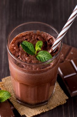 Çikolata, kahve, süt, muz sallamak ahşap arka plan üzerinde. Nane ile güler yüzlü. Milkshake. Protein diyeti. Sağlıklı yiyecek ve içecek konsepti.