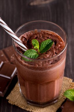 Çikolata, kahve, süt, muz sallamak ahşap arka plan üzerinde. Nane ile güler yüzlü. Milkshake. Protein diyeti. Sağlıklı yiyecek ve içecek konsepti.