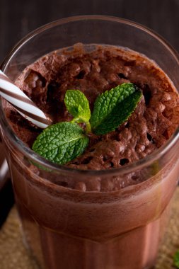 Çikolata, kahve, süt, muz sallamak ahşap arka plan üzerinde. Nane ile güler yüzlü. Milkshake. Protein diyeti. Sağlıklı yiyecek ve içecek konsepti.