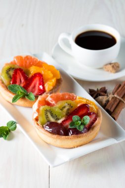 Taze meyve ve meyve ahşap zemin üzerine atmak şekerli tatlı tart. Ahududu, üzüm, çilek, kiraz, kivi, greyfurt ve krema ile lezzetli tatlı pasta.