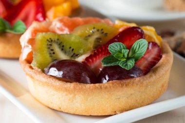 Taze meyve ve meyve ahşap zemin üzerine atmak şekerli tatlı tart. Ahududu, üzüm, çilek, kiraz, kivi, greyfurt ve krema ile lezzetli tatlı pasta.