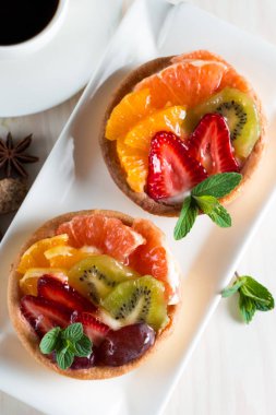 Taze meyve ve meyve ahşap zemin üzerine atmak şekerli tatlı tart. Ahududu, üzüm, çilek, kiraz, kivi, greyfurt ve krema ile lezzetli tatlı pasta.