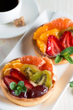 Taze meyve ve meyve ahşap zemin üzerine atmak şekerli tatlı tart. Ahududu, üzüm, çilek, kiraz, kivi, greyfurt ve krema ile lezzetli tatlı pasta.