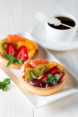 Taze meyve ve meyve ahşap zemin üzerine atmak şekerli tatlı tart. Ahududu, üzüm, çilek, kiraz, kivi, greyfurt ve krema ile lezzetli tatlı pasta.