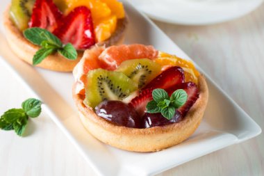 Taze meyve ve meyve ahşap zemin üzerine atmak şekerli tatlı tart. Ahududu, üzüm, çilek, kiraz, kivi, greyfurt ve krema ile lezzetli tatlı pasta.