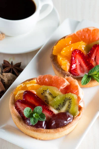 Taze meyve ve meyve ahşap zemin üzerine atmak şekerli tatlı tart. Ahududu, üzüm, çilek, kiraz, kivi, greyfurt ve krema ile lezzetli tatlı pasta.