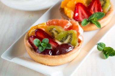 Taze meyve ve meyve ahşap zemin üzerine atmak şekerli tatlı tart. Ahududu, üzüm, çilek, kiraz, kivi, greyfurt ve krema ile lezzetli tatlı pasta.