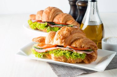 Taze kruvasan veya sandviç salata, jambon, jamon, jambon, salam, peynir, tavuk, domates ahşap arka plan ile. Sabah kahvaltı kavramı. Sağlıklı ve fast food.