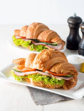 Taze kruvasan veya sandviç salata, jambon, jamon, jambon, salam, peynir, tavuk, domates ahşap arka plan ile. Sabah kahvaltı kavramı. Sağlıklı ve fast food.