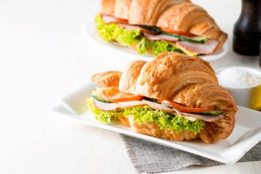 Taze kruvasan veya sandviç salata, jambon, jamon, jambon, salam, peynir, tavuk, domates ahşap arka plan ile. Sabah kahvaltı kavramı. Sağlıklı ve fast food.
