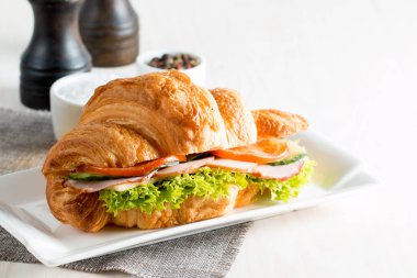 Taze kruvasan veya sandviç salata, jambon, jamon, jambon, salam, peynir, tavuk, domates ahşap arka plan ile. Sabah kahvaltı kavramı. Sağlıklı ve fast food.