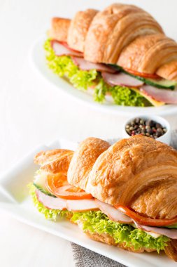 Taze kruvasan veya sandviç salata, jambon, jamon, jambon, salam, peynir, tavuk, domates ahşap arka plan ile. Sabah kahvaltı kavramı. Sağlıklı ve fast food.