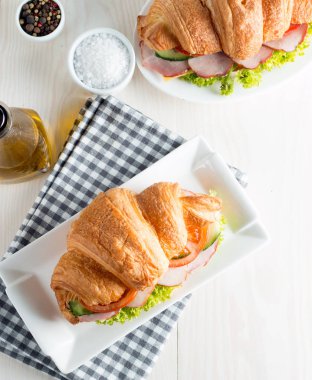 Taze kruvasan veya sandviç salata, jambon, jamon, jambon, salam, peynir, tavuk, domates ahşap arka plan ile. Sabah kahvaltı kavramı. Sağlıklı ve fast food.
