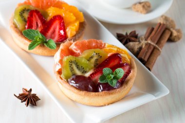 Taze meyve ve meyve ahşap zemin üzerine atmak şekerli tatlı tart. Ahududu, üzüm, çilek, kiraz, kivi, greyfurt ve krema ile lezzetli tatlı pasta.