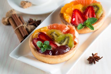 Taze meyve ve meyve ahşap zemin üzerine atmak şekerli tatlı tart. Ahududu, üzüm, çilek, kiraz, kivi, greyfurt ve krema ile lezzetli tatlı pasta.