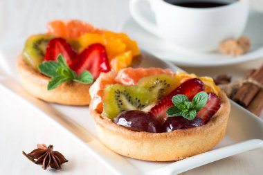 Taze meyve ve meyve ahşap zemin üzerine atmak şekerli tatlı tart. Ahududu, üzüm, çilek, kiraz, kivi, greyfurt ve krema ile lezzetli tatlı pasta.