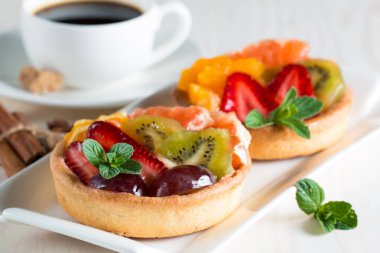 Taze meyve ve meyve ahşap zemin üzerine atmak şekerli tatlı tart. Ahududu, üzüm, çilek, kiraz, kivi, greyfurt ve krema ile lezzetli tatlı pasta.