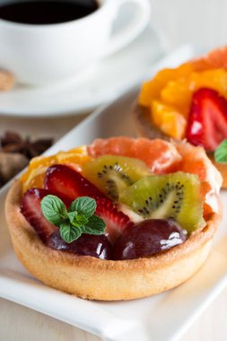 Taze meyve ve meyve ahşap zemin üzerine atmak şekerli tatlı tart. Ahududu, üzüm, çilek, kiraz, kivi, greyfurt ve krema ile lezzetli tatlı pasta.