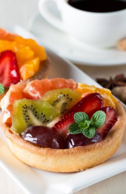 Taze meyve ve meyve ahşap zemin üzerine atmak şekerli tatlı tart. Ahududu, üzüm, çilek, kiraz, kivi, greyfurt ve krema ile lezzetli tatlı pasta.