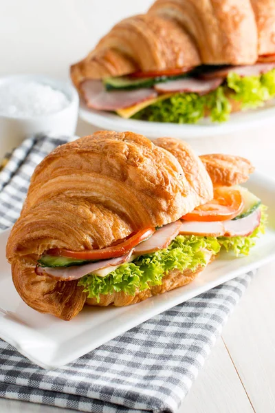 Taze kruvasan veya sandviç salata, jambon, jamon, jambon, salam, peynir, tavuk, domates ahşap arka plan ile. Sabah kahvaltı kavramı. Sağlıklı ve fast food.
