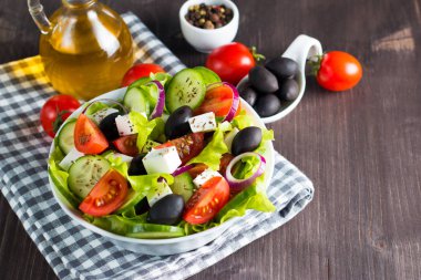 Kiraz domates, ruccola, roka, beyaz peynir, zeytin, salatalık, soğan ve baharat taze Yunan salatası yaptı. Sezar salatası ahşap arka plan üzerinde beyaz bir kase. Sağlıklı organik beslenme gıda kavramı.