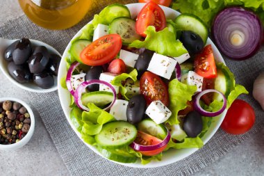 Kiraz domates, ruccola, roka, beyaz peynir, zeytin, salatalık, soğan ve baharat taze Yunan salatası yaptı. Sezar salatası ahşap arka plan üzerinde beyaz bir kase. Sağlıklı organik beslenme gıda kavramı.