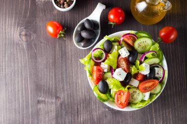 Kiraz domates, ruccola, roka, beyaz peynir, zeytin, salatalık, soğan ve baharat taze Yunan salatası yaptı. Sezar salatası ahşap arka plan üzerinde beyaz bir kase. Sağlıklı organik beslenme gıda kavramı.