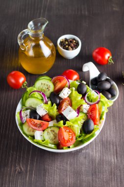 Kiraz domates, ruccola, roka, beyaz peynir, zeytin, salatalık, soğan ve baharat taze Yunan salatası yaptı. Sezar salatası ahşap arka plan üzerinde beyaz bir kase. Sağlıklı organik beslenme gıda kavramı.