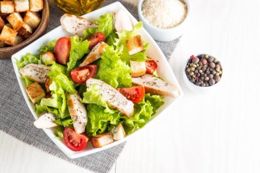 Taze salata domates, ruccola, tavuk göğsü, yumurta, roka, kraker ve baharat yapılmış. Ahşap arka plan üzerinde beyaz, şeffaf bir kasede Sezar salatası