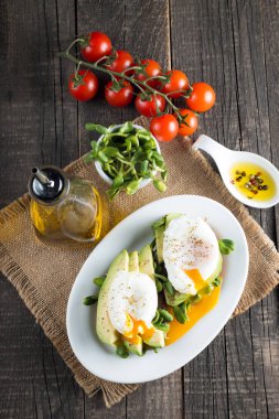 Avokado tost, kiraz domates ahşap arka plan üzerinde. Kahvaltı tost avokado, Vejetaryen gıda, sağlıklı beslenme kavramı ile. Avokado ve haşlanmış yumurta ile sağlıklı sandviç.