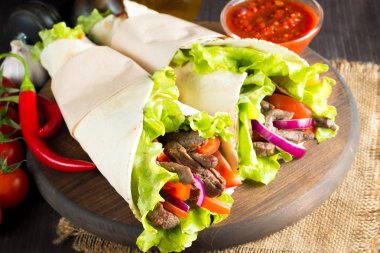Fotoğraf Meksika sandviç gıda, börek, fajita, tacos, paket tortilla, sığır eti, tavuk, taze sebze rustik ahşap zemin üzerine yapılmış. Fast food kavramı. Sağlıklı yemek yemek. Kopya alanı. 