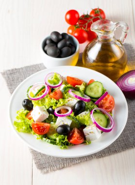 Kiraz domates, ruccola, roka, beyaz peynir, zeytin, salatalık, soğan ve baharat taze Yunan salatası yaptı. Sezar salatası ahşap arka plan üzerinde beyaz bir kase. Sağlıklı organik beslenme gıda kavramı.