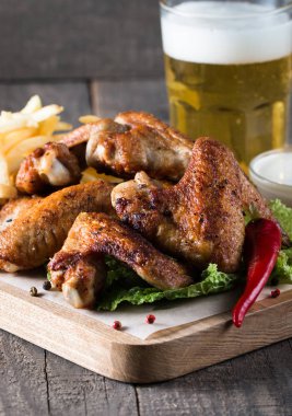 Yakın çekim fotoğraf Barbekü tavuk kanatlı patates ve bira. Barbekü soslar, ketçap, mayonez etli. Hızlı ve abur cubur kavramı. 