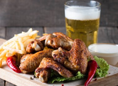 Yakın çekim fotoğraf Barbekü tavuk kanatlı patates ve bira. Barbekü soslar, ketçap, mayonez etli. Hızlı ve abur cubur kavramı. 