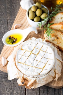Pişmiş camembert peyniri. Taze Brie peyniri ve bir dilim fındık, tatlım, biberiye ile ahşap bir gemide, baget ekmek ızgara tost ve yaprakları. Peynir Brie türü. İtalyan, Fransız peynir.