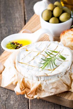 Pişmiş camembert peyniri. Taze Brie peyniri ve bir dilim fındık, tatlım, biberiye ile ahşap bir gemide, baget ekmek ızgara tost ve yaprakları. Peynir Brie türü. İtalyan, Fransız peynir.