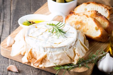 Pişmiş camembert peyniri. Taze Brie peyniri ve bir dilim fındık, tatlım, biberiye ile ahşap bir gemide, baget ekmek ızgara tost ve yaprakları. Peynir Brie türü. İtalyan, Fransız peynir.