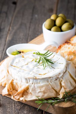Pişmiş camembert peyniri. Taze Brie peyniri ve bir dilim fındık, tatlım, biberiye ile ahşap bir gemide, baget ekmek ızgara tost ve yaprakları. Peynir Brie türü. İtalyan, Fransız peynir.