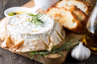 Pişmiş camembert peyniri. Taze Brie peyniri ve bir dilim fındık, tatlım, biberiye ile ahşap bir gemide, baget ekmek ızgara tost ve yaprakları. Peynir Brie türü. İtalyan, Fransız peynir.