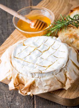 Pişmiş camembert peyniri. Taze Brie peyniri ve bir dilim fındık, tatlım, biberiye ile ahşap bir gemide, baget ekmek ızgara tost ve yaprakları. Peynir Brie türü. İtalyan, Fransız peynir.