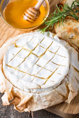 Pişmiş camembert peyniri. Taze Brie peyniri ve bir dilim fındık, tatlım, biberiye ile ahşap bir gemide, baget ekmek ızgara tost ve yaprakları. Peynir Brie türü. İtalyan, Fransız peynir.