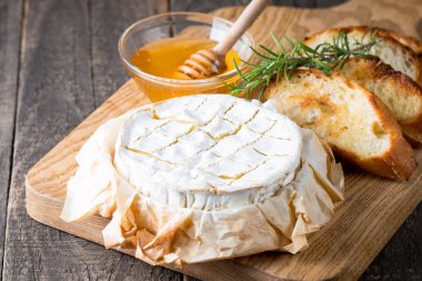 Pişmiş camembert peyniri. Taze Brie peyniri ve bir dilim fındık, tatlım, biberiye ile ahşap bir gemide, baget ekmek ızgara tost ve yaprakları. Peynir Brie türü. İtalyan, Fransız peynir.