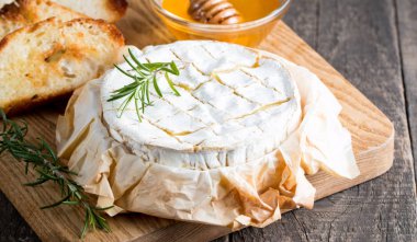 Pişmiş camembert peyniri. Taze Brie peyniri ve bir dilim fındık, tatlım, biberiye ile ahşap bir gemide, baget ekmek ızgara tost ve yaprakları. Peynir Brie türü. İtalyan, Fransız peynir.